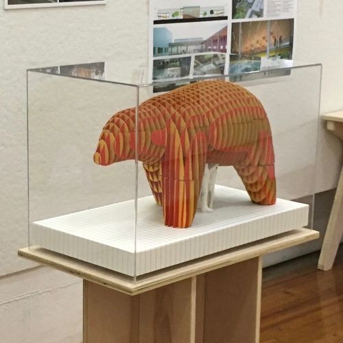 A bear sculpture is displayed in a glass case.