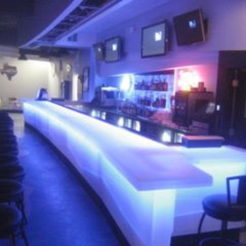 A bar with lights and chairs in the back.