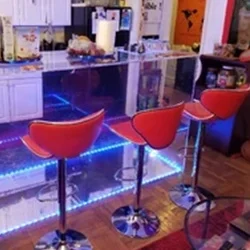 5 Three red stools in front of a bar with blue lights.